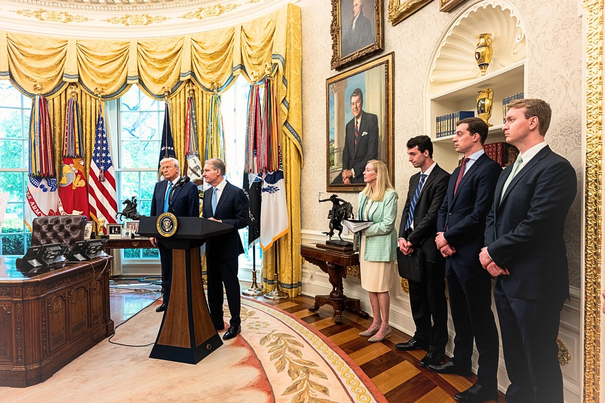 Paul S. Atkins parla dal leggio nello Studio Ovale accanto al presidente Donald Trump, davanti a un piccolo gruppo di persone in piedi